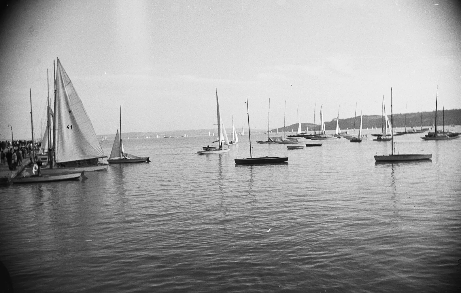 Black and white view across the water of Balatonfured harbour with sailing boats at anchor